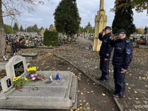 Zdjęcie przedstawia policjantów oddających hołd zmarłemu przed pomnikiem