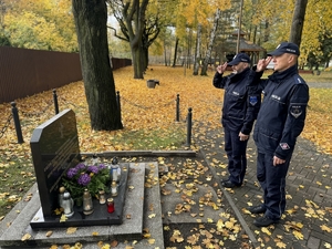 Zdjęcie przedstawia policjantów oddających hołd zmarłemu przed pomnikiem