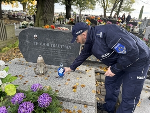 Zdjęcie przedstawia policjanta stawiającego znicz na pomniku