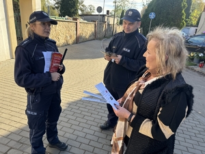 Zdjęcie przedstawia policjantów wręczających ulotki przechodniom