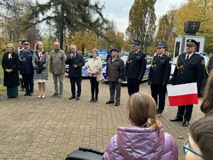 Zdjęcie przedstawia mężczyznę podczas przemowy. Obok niego stoją uczestnicy wydarzenia