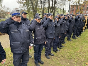 Zdjęcie przedstawia policjantów salutujących podczas śpiewania hymny państwowego