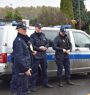 Zdjęcie przedstawia policjantów stojących przy radiowozie