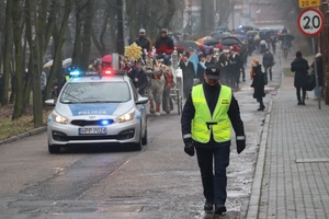 Zdjęcie przedstawia policyjny radiowóz pilotujący korowód  oraz strażnika miejskiego