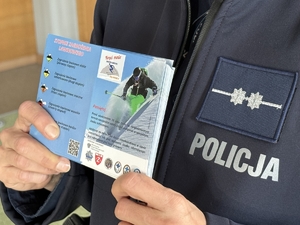 Zdjęcie przedstawia policjantkę trzymającą ulotkę w ręku