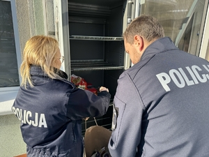 Zdjęcie policjantów wkładających produkty do lodówki dla potrzebujących