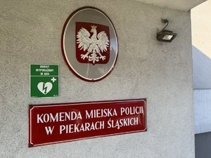 Zdjęcie przedstawia informację o defibrylatorze umieszczoną na budynku Policji