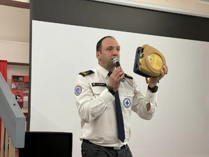 Zdjęcie przedstawia ratownika wodnego podczas prezentacji automatycznego defibrylatora zewnętrznego
