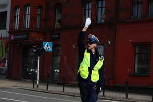 Zdjęcie przedstawia policjanta regulującego ruchem na skrzyżowaniu