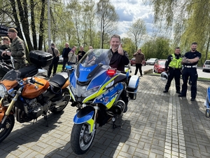 Zdjęcie przedstawia kobietę siedzącą na policyjnym motocyklu