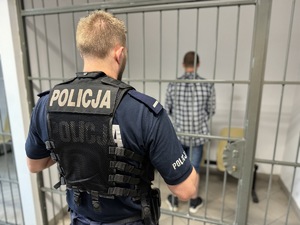 Zdjęcie przedstawia policjanta oraz sprawcę kradzieży w policyjnym areszcie