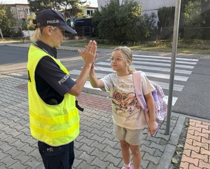 Zdjęcie przedstawia policjantów oraz dzieci podczas drogi do szkoły.