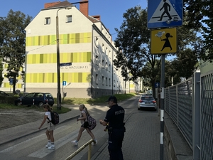 Zdjęcie przedstawia policjantów oraz dzieci podczas drogi do szkoły.