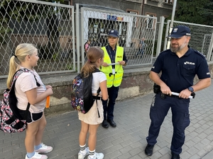 Zdjęcie przedstawia policjantów oraz dzieci podczas drogi do szkoły.