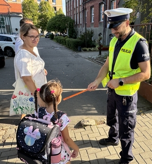 Zdjęcie przedstawia policjantów oraz dzieci podczas drogi do szkoły.