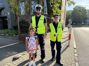 Zdjęcie przedstawia policjantów oraz dzieci podczas drogi do szkoły.