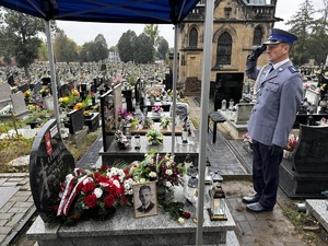 Zdjęcie policjanta oddającego hołd przed grobem