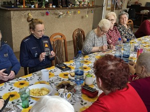 Zdjęcie policjantów i seniorów podczas wizyty w klubie seniora