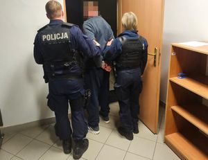 Zdjęcie policjantów prowadzących zatrzymanego mężczyznę