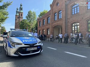 Zdjęcie radiowozu policyjnego na tle piekarskiej bazyliki