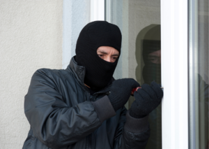 Grafika przedstawia mężczyznę próbującego włamać się do domu