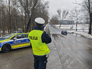 Policjant stoi w trakcie kontroli prędkości kierujących.