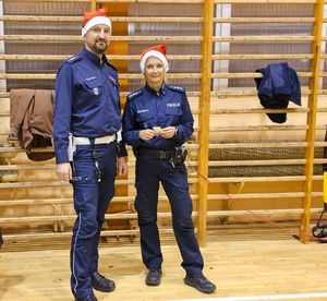 Zdjęcie policjantów oraz dzieci na hali sportowej podczas spotkania "Sportowy Mikołaj"