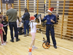 Zdjęcie policjantów oraz dzieci na hali sportowej podczas spotkania "Sportowy Mikołaj"