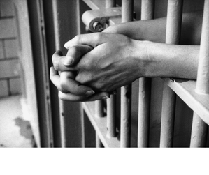 Grafika przedstawia mężczyznę za kratami