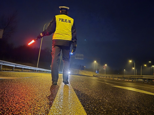 Zdjęcie policjanta na drodze z latarką podczas zatrzymywania pojazdu
