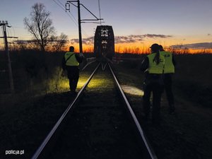 Zdjęcie nocą policjantów na torowisku