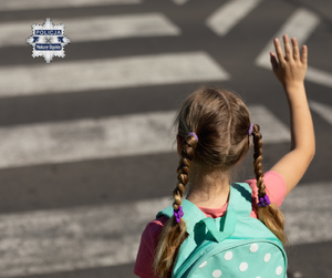 Dziecko z ręką uniesioną do góry podczas przechodzenia przez przejście dla pieszych