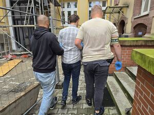 policjanci prowadza zatrzymanego mężczyznę