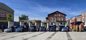 policjanci strażacy oraz strażnicy miejscy podczas oddania hołdu poległemu policjantowi stoją przed radiowozami